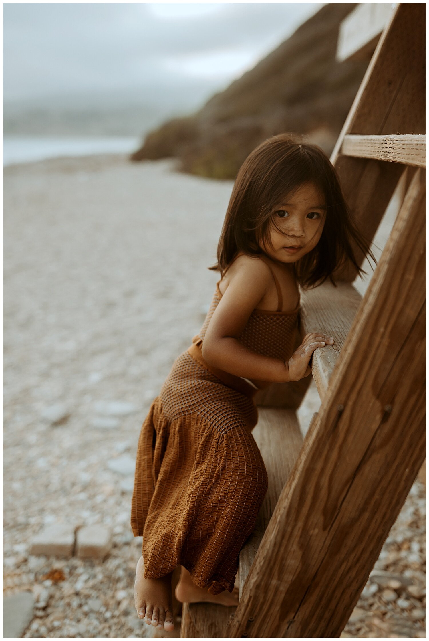 little sister playing during family photo shoot on Los Angeles beach